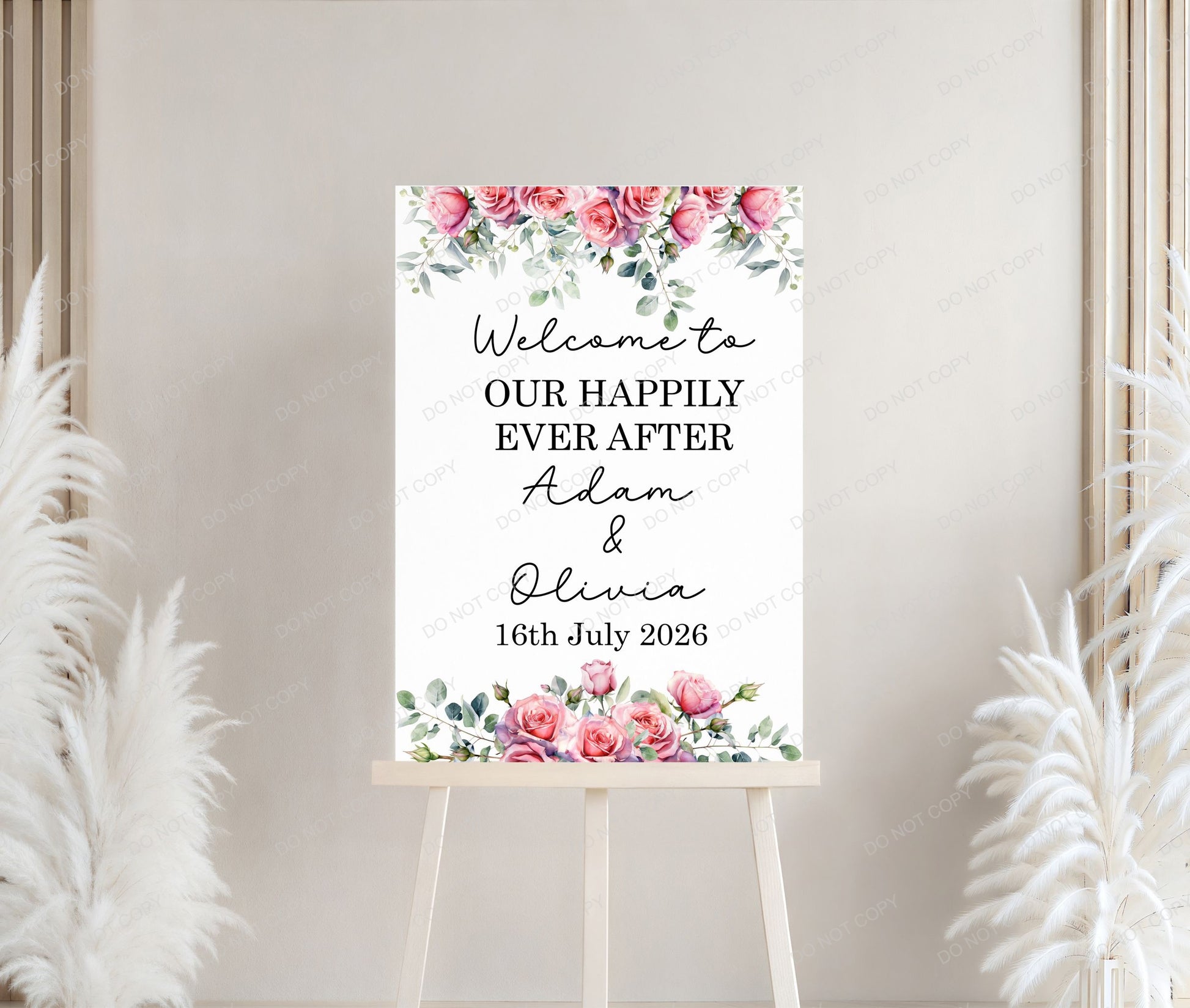 Wedding welcome sign with floral design and personalized text on a white stand against a neutral background.