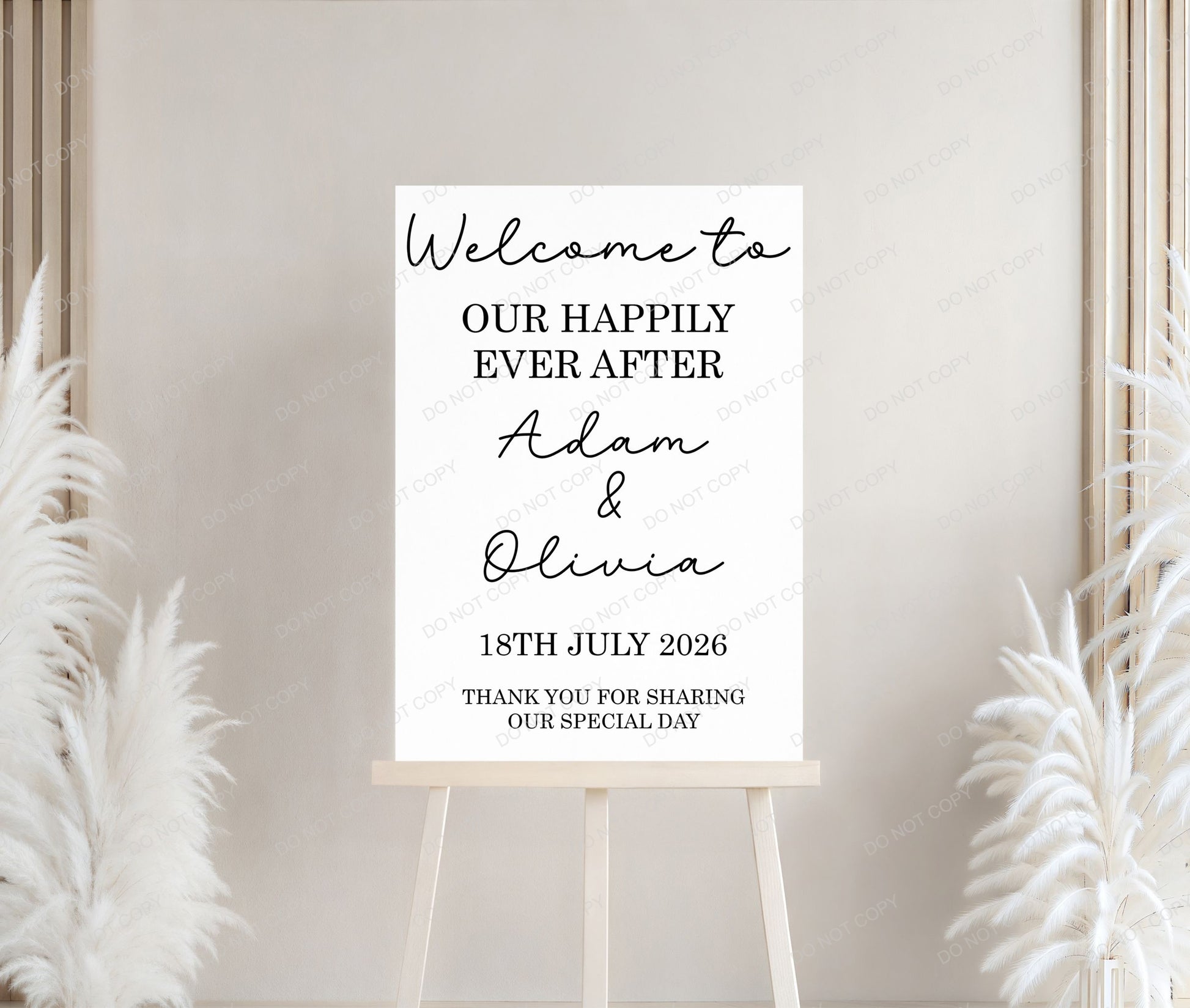 Wedding welcome sign on a stand with decorative plants against a neutral wall.